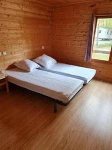 two beds in a wooden room with a window at ZEcamping 3 dog friendly avec piscine au bord du lac de la Thésauque in Nailloux