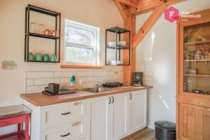 a kitchen with white cabinets and a sink and a window at Le Pèlerin - Chalet rustique Écoresponsable en nature - Estrie in Notre-Dame-Des-Bois
