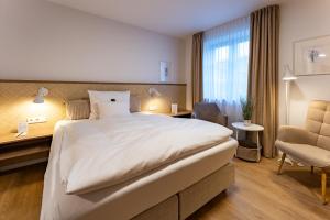 a hotel room with a bed and a desk and a chair at Wellings Romantik Hotel zur Linde in Moers
