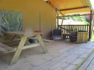 a picnic table and bench in a tent at ZEcamping 3 étoiles pet friendly en bord de rivière avec une plage de sable in Jumilhac-le-Grand
