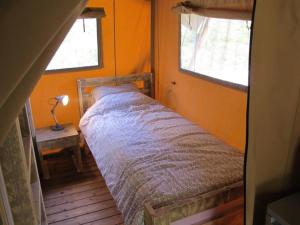 a small bed in a room with two windows at ZEcamping 3 étoiles pet friendly en bord de rivière avec une plage de sable in Jumilhac-le-Grand +49 photos