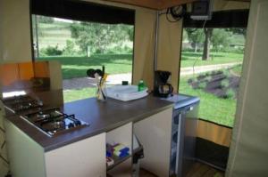 a small kitchen with a stove and a window at ZEcamping 3 étoiles dog friendly piscine chauffée en bordure de l'Allier in Lespéron