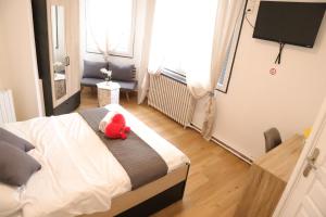 a red teddy bear sitting on a bed in a bedroom at Hôtel & Restaurant ISVARA in Breteuil