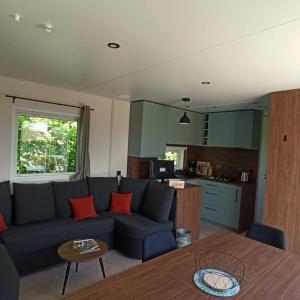 a living room with a blue couch and a kitchen at ZEcamping 3 étoiles animaux acceptés sauna piscine couverte in Mont-près-Chambord
