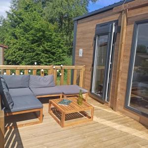 a deck with a couch and a coffee table at ZEcamping 3 étoiles animaux acceptés sauna piscine couverte in Mont-près-Chambord