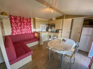 a living room with a red couch and a table at Camping 3 étoiles - ccaidff in Beaulieu