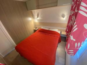 a small room with a bed with a red blanket at Camping 3 étoiles - ccaidff in Beaulieu
