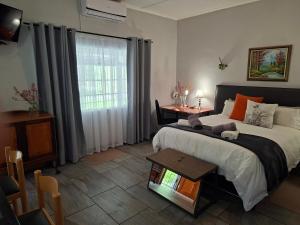 a bedroom with a bed and a table and a window at Altenburgh Accommodation - Apartments in Somerset East