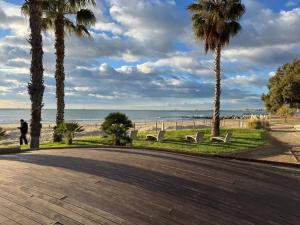 a person walking down a path near the beach with palm trees at VillaBrisaeta, villa costera a un paso de todo. in Benicàssim