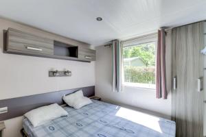 a small bedroom with a bed and a window at ZEcamping 4 pet friendly club enfant piscine bar et restanrant in La Bastide-de-Sérou