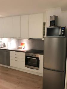 a kitchen with white cabinets and a stainless steel refrigerator at Koselig og praktisk studioleilighet in Svolvær