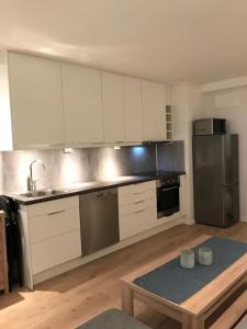 a kitchen with white cabinets and stainless steel appliances at Koselig og praktisk studioleilighet in Svolvær