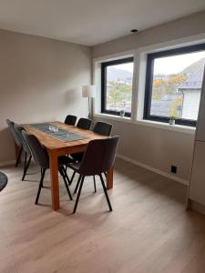 a dining room with a table and chairs and two windows at Sentral toppleilighet 3.etg 4 pers in Svolvær