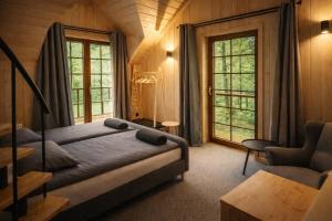 a bedroom with a bed and a chair and windows at Leśna Przystań apartamenty dwupoziomowe nad jeziorem in Węgorzewo