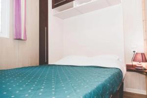 a bedroom with a bed with a green comforter at ZEcamping 3 étoiles animaux acceptés espace aquatique in Moncontour-de-Poitou