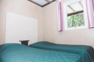 a bedroom with a green bed and a window at ZEcamping 3 étoiles animaux acceptés espace aquatique in Moncontour-de-Poitou