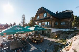 a group of tables and umbrellas in front of a log house at Cabana Vitus Panzió in Harghita-Băi +15 photos