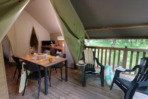a dining room with a table and chairs on a balcony at ZEcamping 3 dog friendly salle fitness piscine in Vensac