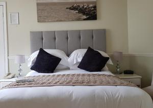 ein Schlafzimmer mit einem großen Bett mit weißen Laken und Kissen in der Unterkunft Fernhill Hotel in Lyme Regis
