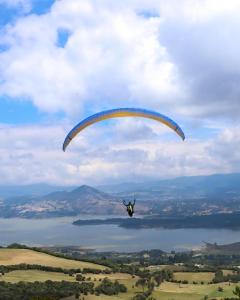 a person riding a parachute over a body of water at Glamping Claro de Luna in Guatavita