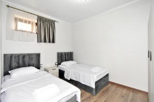 two beds in a room with white walls and wooden floors at Riposo Hotel Armenia in Pʼarakʼar