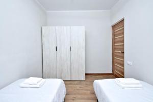 a white room with two beds and a cabinet at Riposo Hotel Armenia in Pʼarakʼar