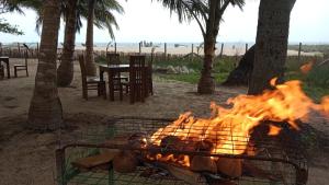a fire in a grill with palm trees and a table at Pasikuda Shalom Beach Villa in Kalkudah