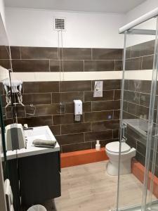 a bathroom with a toilet and a sink and a shower at Hôtel du Centre in Gueugnon
