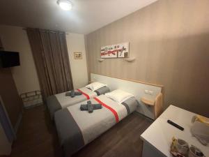 a hotel room with two beds and a desk at Hôtel du Centre in Gueugnon