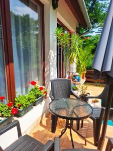 a patio with a table and chairs and flowers at Villa Vadása Vendégház in Hegyhátszentjakab +9 photos