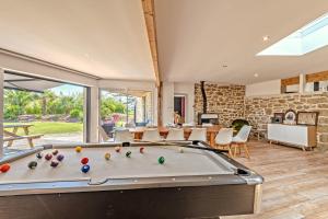 a pool table in a living room with a stone wall at Weekend dans la villa Léonie in Kerlouan