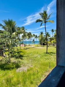 a view of a field with palm trees and the ocean at Flats Coco Coral in Barra Grande