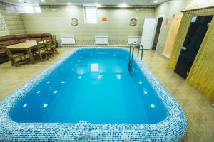 a large blue pool in a room with a table at Hotel Sokol in Sorochinsk