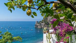 a view of the ocean from a cliff with flowers at La Dolce Vita a Positano boutique hotel in Positano