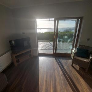 a living room with a television and a sliding glass door at Sea View Apartment in Cobh