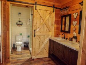 a bathroom with a wooden door with a sink and a toilet at Bavarian Hideaway 25 in Helen +15 photos