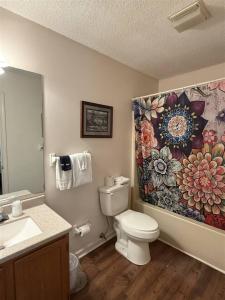a bathroom with a toilet and a flower shower curtain at Rivers Edge 803A in Helen