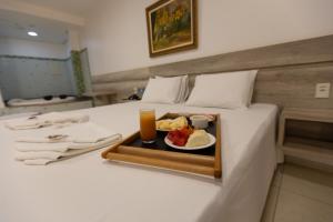a tray with a plate of food on a bed at Aldeias Palace Hotel in Tucuma