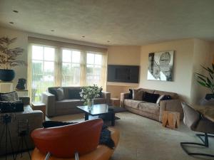 a living room with two couches and a table at Villa Pura Vida in Oud-Ade