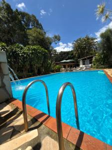 a blue swimming pool with two metal rails next to it at Pousada das Brumas in Brumadinho