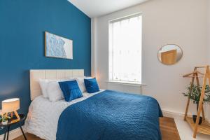 a blue bedroom with a bed and a window at Harbour-View Apartment Facing HMS Warrior in Portsmouth