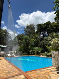 a blue swimming pool with the eiffel tower in the background at Pousada das Brumas in Brumadinho