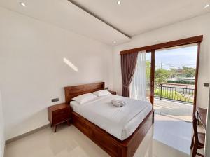 a bedroom with a bed and a large window at Paramulia house in Canggu