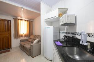 a kitchen with a sink and a couch in a room at Pousada da Árvore in Boicucanga