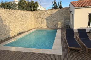 a swimming pool with two chairs and a wall at Le havre des embruns in Saint-Xandre