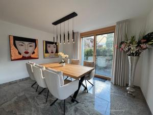 a dining room with a wooden table and white chairs at Arenenberg-Panorama in Salenstein