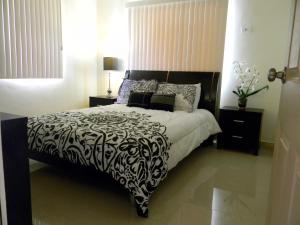 1 dormitorio con 1 cama con edredón blanco y negro en Pedro Villas, en Tamuning