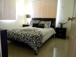 a bedroom with a bed with a black and white comforter at Pedro Villas in Tamuning