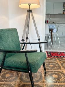 a green chair sitting next to a table with a lamp at Ethno House Andrej in Korbovo