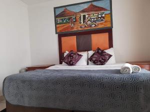 a bedroom with a bed with a painting on the wall at THE ROSE BnB in Soweto
